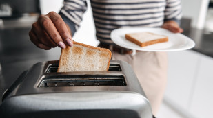 Frau nimmt Scheibe aus Toaster