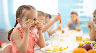 Kind sitzt an einem Tisch und isst