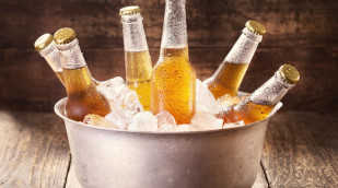 Kalten Bierflaschen in Eimer mit Eis auf Holztisch